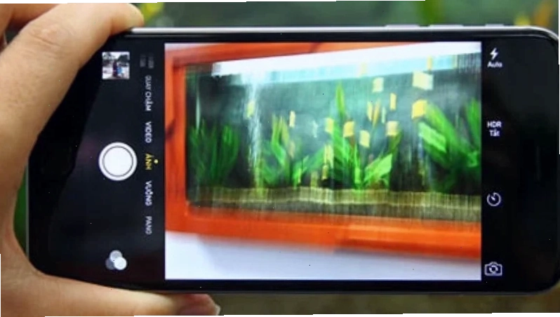 Ảnh chụp cận cảnh một ống kính camera điện thoại bị bám bụi và vân tay gây mờ nhòe