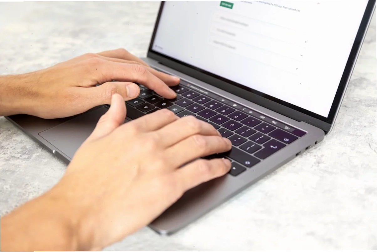 Hai bàn tay gõ trên laptop khi nhờ trợ lý AI viết công thức Excel